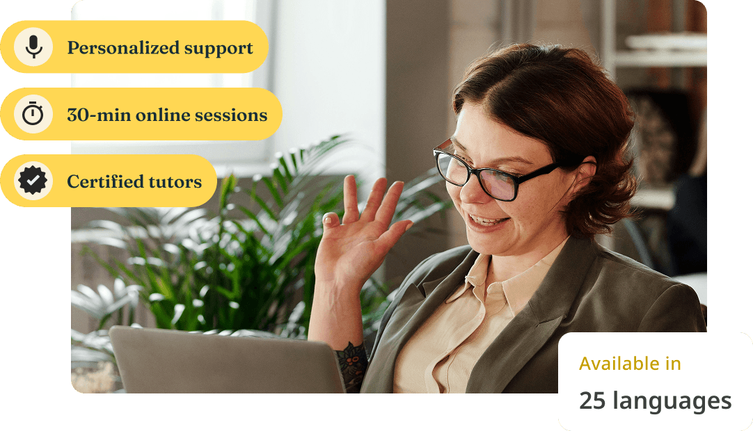 A woman waves and smiles at her laptop during an online tutoring session