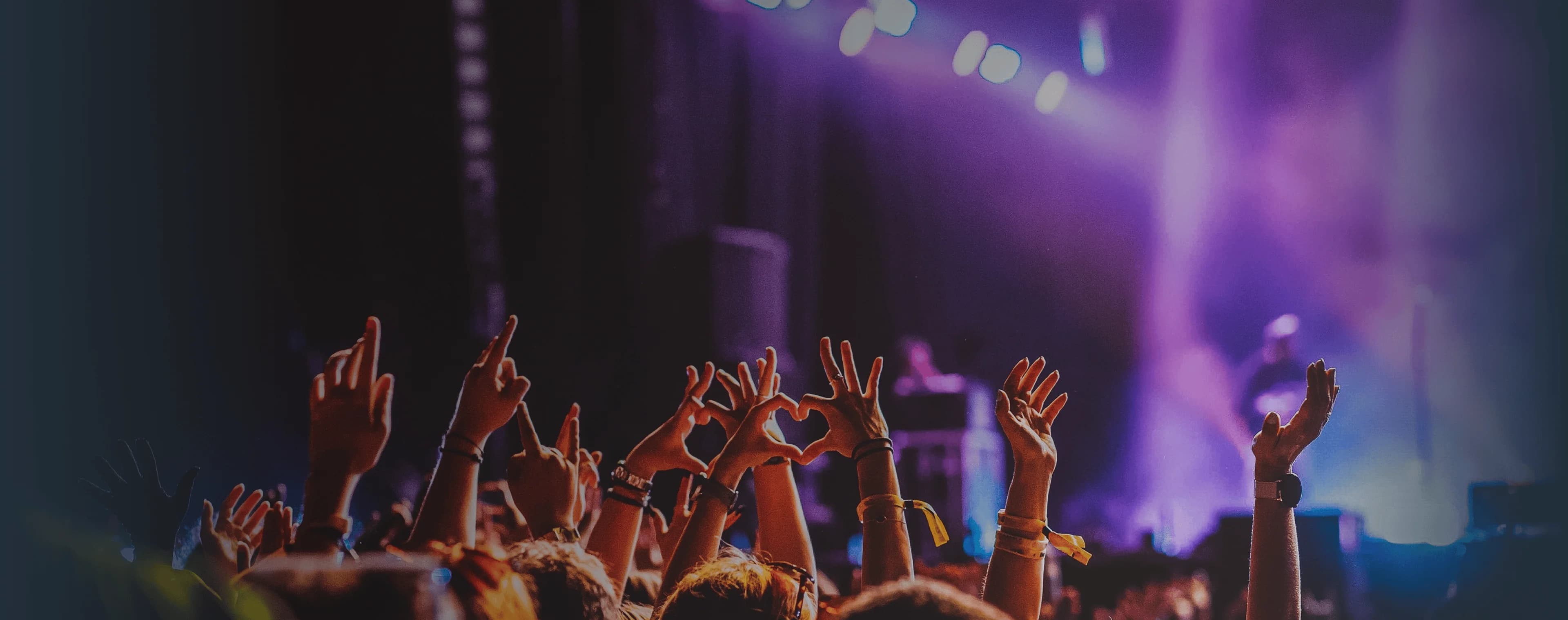 Crowd raises hands in excitement at live music performance. Overlaid is the German word "Konzert" with its English translation, "concert".