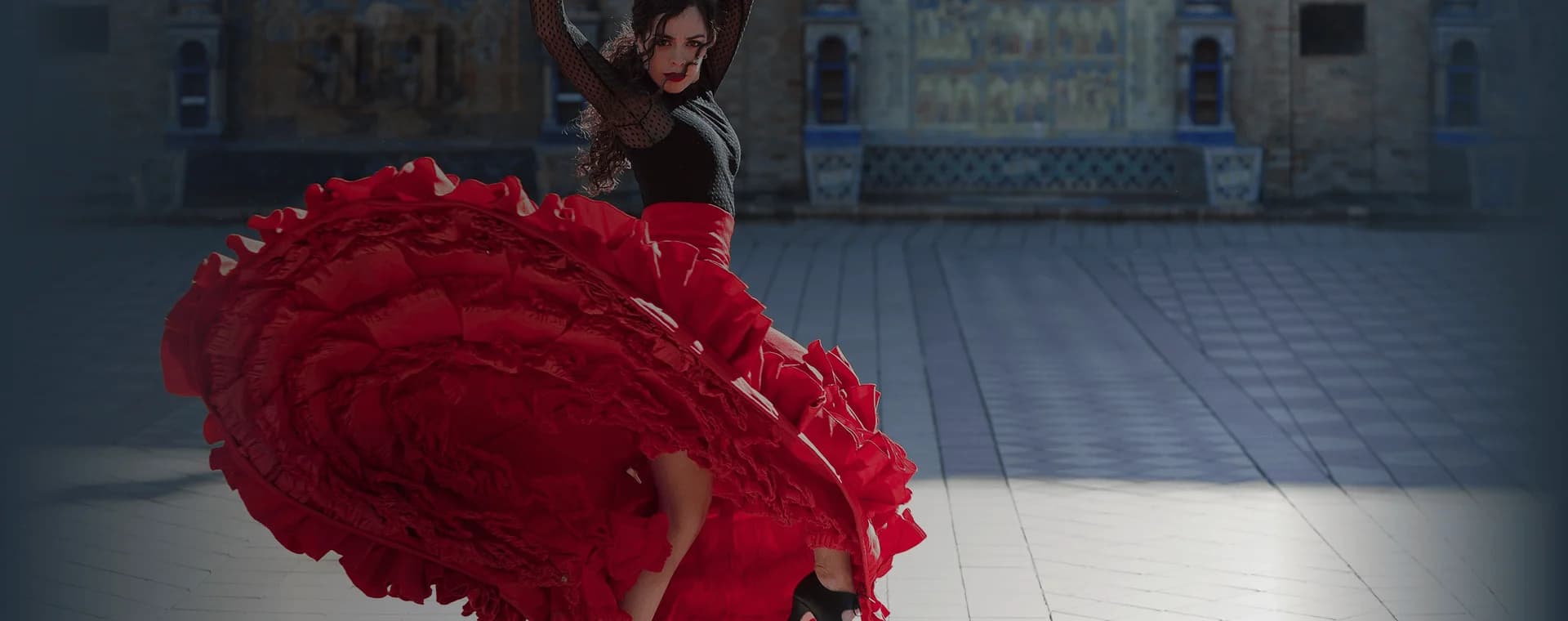Flamenco dancer twirls in front of grand building backdrop. Overlaid is the Spanish word "bailar" with its English translation, "to dance".
