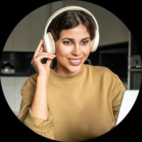 A woman wearing headphones and smiling while looking at a screen, representing a live or AI-powered tutoring session